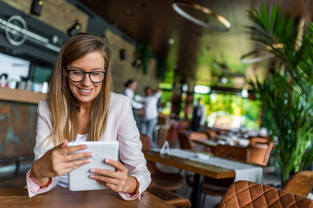 pretty young female manager using modern digital tablet at cafe - reading newspaper 30s adult imagens e fotografias de stock