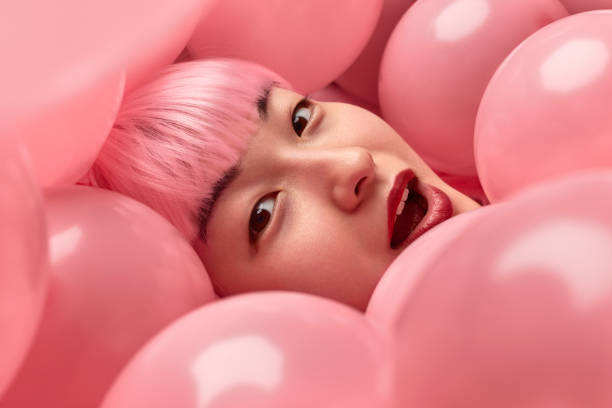 istock Amazed Asian woman under pink balloons 1165682550
