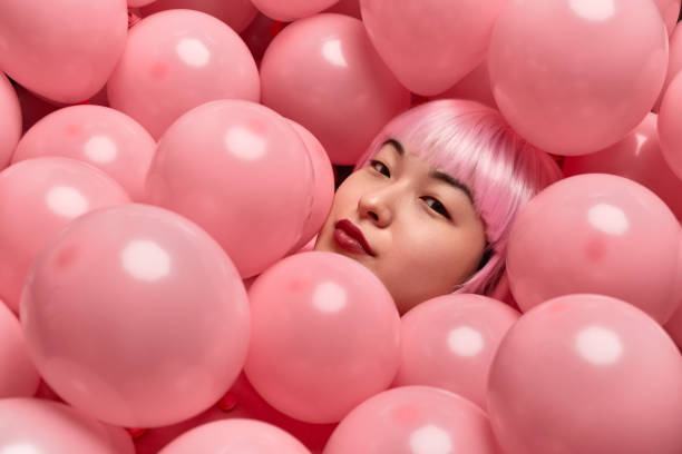 istock Attractive lady in pink wig lying under balloons 1165682552