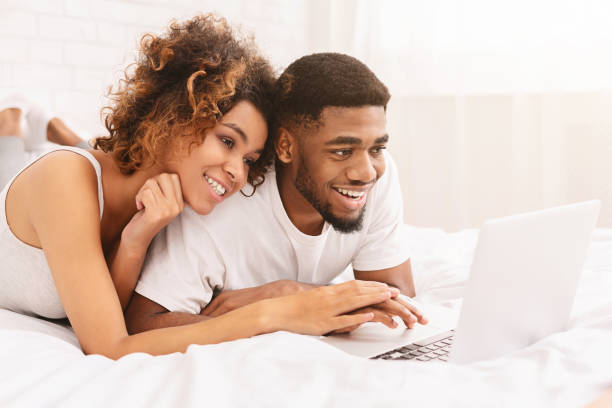 istock Young black couple lying on bed and using laptop 1165682810