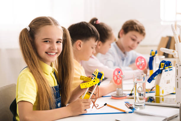 istock Adorable schoolgirl holding robot model at STEM classroom 1165682886