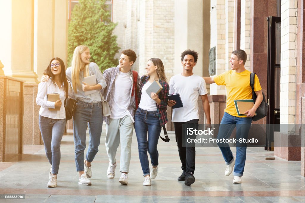 Happy students walking together in campus, having break Diverse students walking together in campus, having break after classes Student Stock Photo