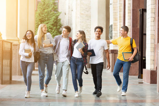 счастливые студенты ходят вместе в кампусе, имея перерыв - university education walking teenage girls стоковые фото и изображения
