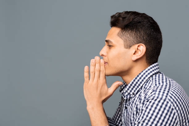 Young Man Praying And Asking For Something, Side View Upset Young Man Praying And Asking For Something On Gray Background. Side View, Copy Space man regret stock pictures, royalty-free photos & images