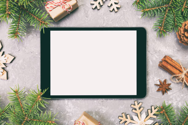 istock Digital tablet mock up with rustic Christmas gray cement background decorations for app presentation. top view with copy space. Toned 1165687140