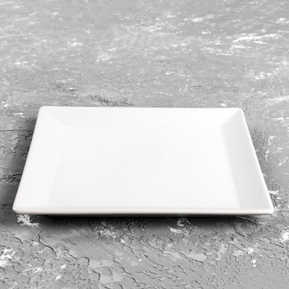 White square Plate on grey table background. Perspective view.
