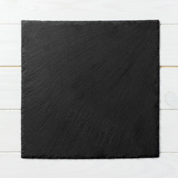 istock Black square plate on wooden background, top view, copy space 1165687424