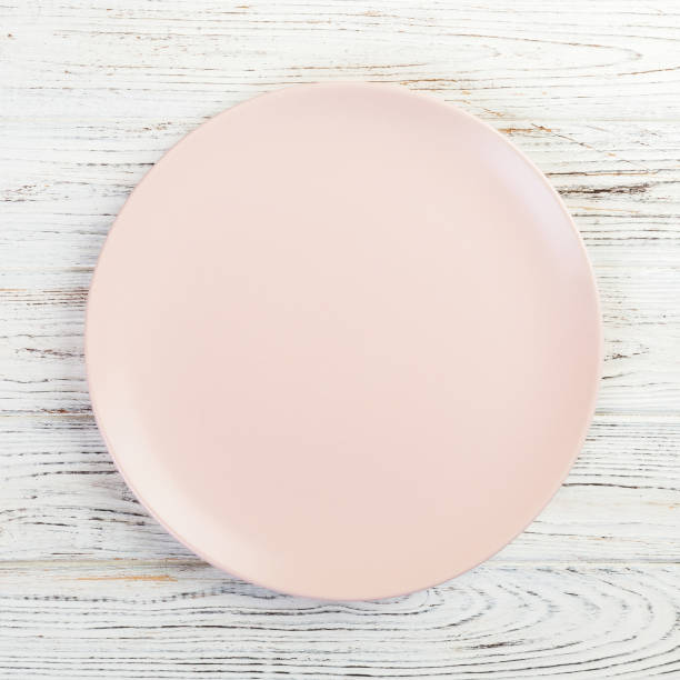 istock Empty pink or coral round plate on wooden table background. Top view, template for your design 1165687583