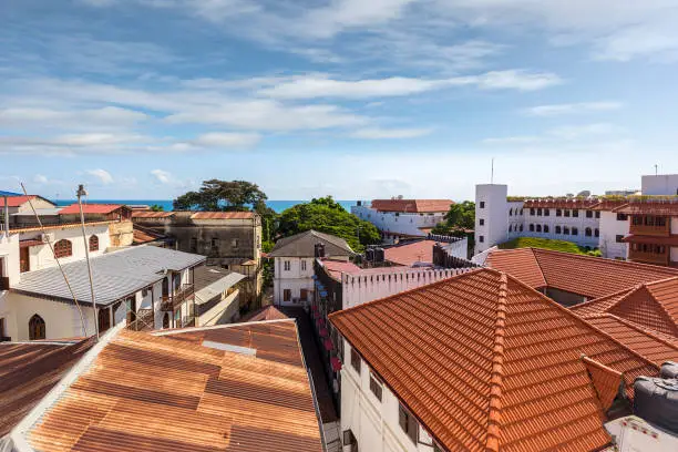 rooftops of zanzibar town stonetown showing the corrugated iron roofs colorful and weathered in the late afternoon morning light showing the distant ocean and horizon