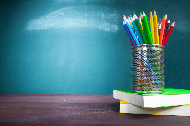 istock Textbooks and pencil holder on school desk with blackboard 1165690062