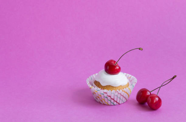istock Cupcake with red cherry on pink background with copy space. 1165692403