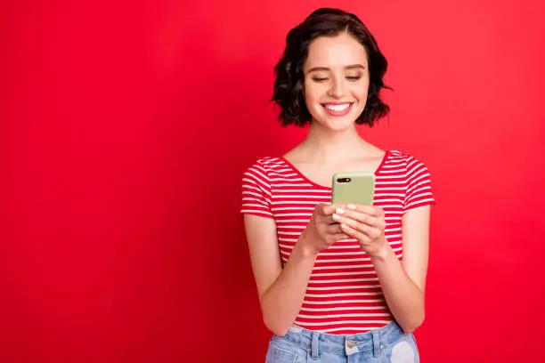Portrait of her she nice attractive pretty lovely cheerful cheery addicted, wavy-haired teen girl spending free time using wi-fi isolated over bright vivid shine red background