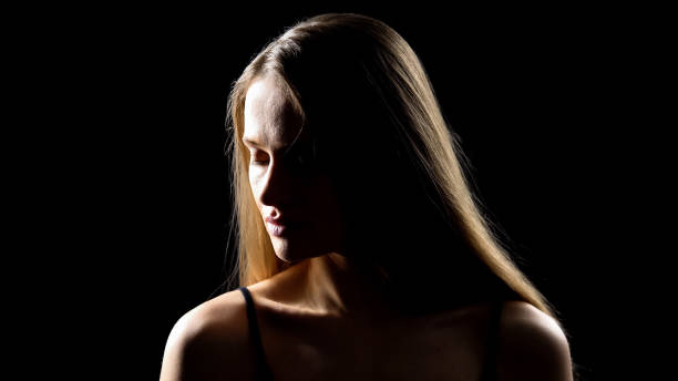 istock Beautiful young lady turning face to camera against black background, femininity 1165701185