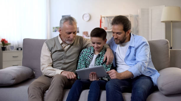 istock Grandfather and father scrolling tablet checking school marks in online register 1165701436
