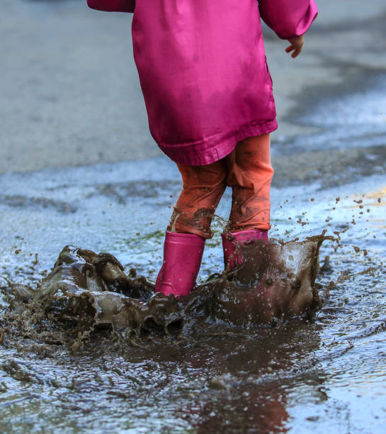 istock Playful child outdoor jump into puddle in boot after rain 1165701463
