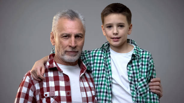 istock Senior male and little boy hugging and looking to camera, friendly relations 1165701477