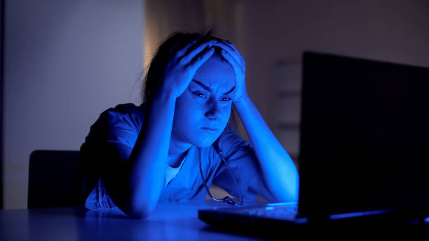 istock Tired young doctor working on computer at night, preparing for examination 1165702418