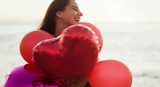 Cropped shot of a beautiful young woman holding heart-shaped balloons