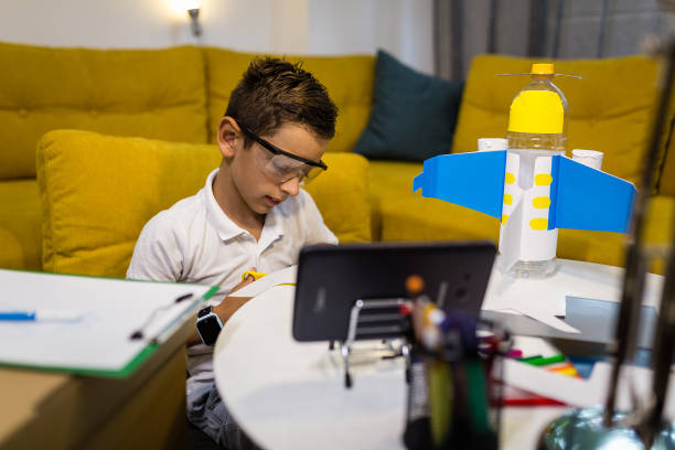 istock Boy is recycling paper by cutting it and making toys from it 1165703052