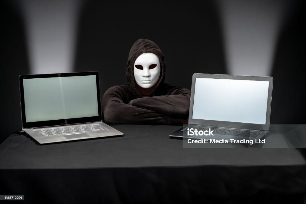 Computer Hacker Camera Masked Hacker Looking At Camera Between Two Laptops Stock Photo ...