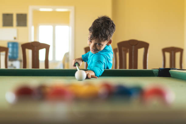 молодой мальчик играет в бильярд в зоне отдыха - child sport playing pool game стоковые фото и изображения
