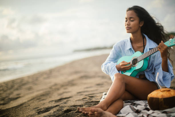 istock Woman playing ukelele on the beach 1165715115