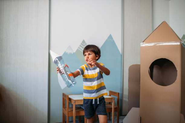 очаровательный маленький мальчик, играющий с ракетой дома - recycling green environment superhero стоковые фото и изображения