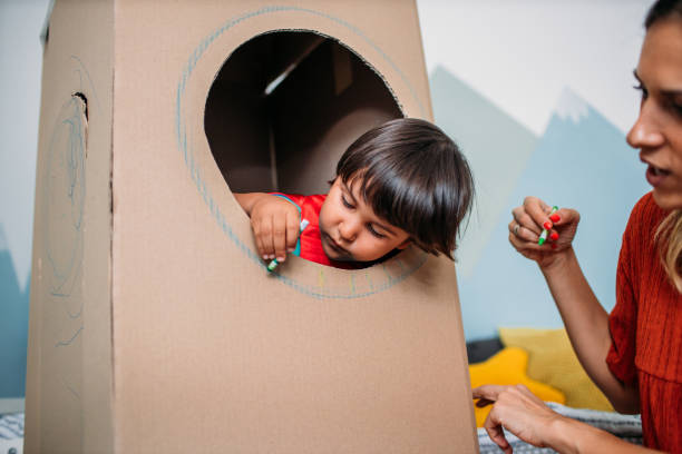 istock Adorable Little Boy Dressed Like A Superhero Decorating Cardboard Rocket At Home 1165716206
