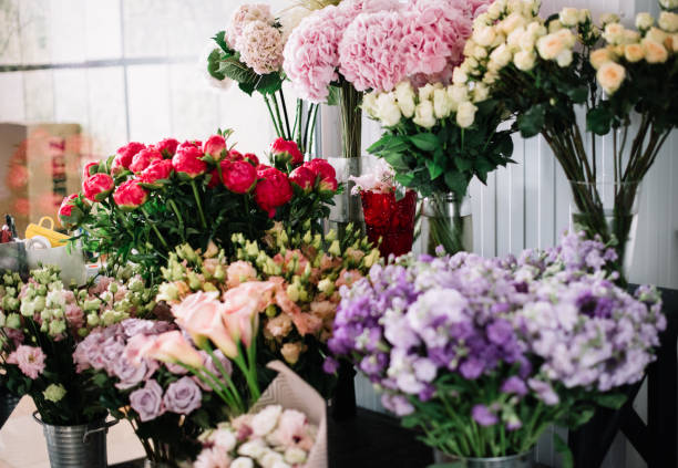 Beautiful blossoming fresh flowers at the florist shop: roses, hydrangea, matthiola, peony, calla lilies on the shelves stock photo