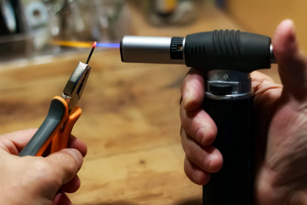 istock a man heating up a nail, using a torch gun in his workshop 1165724592
