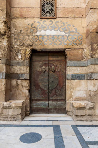 istock Wooden decorated copper plated door and stone bricks wall, Old Cairo, Egypt 1165727077
