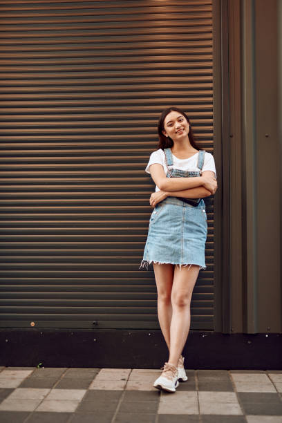 istock Young happy asian lady leaning on wall on street 1165729480
