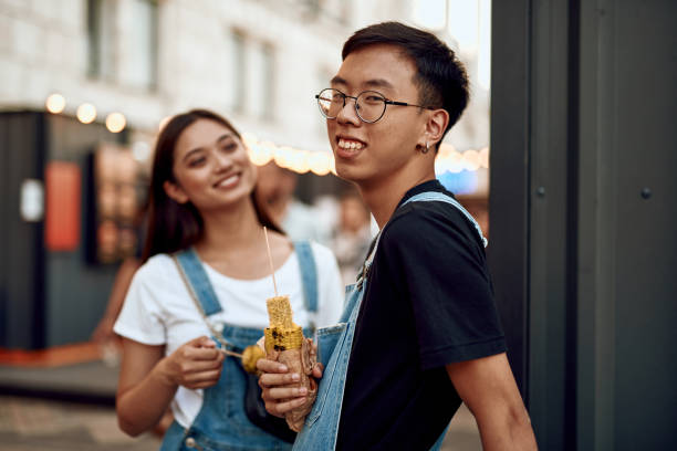 istock Young asian couple talking outdoot with grill corn 1165729635
