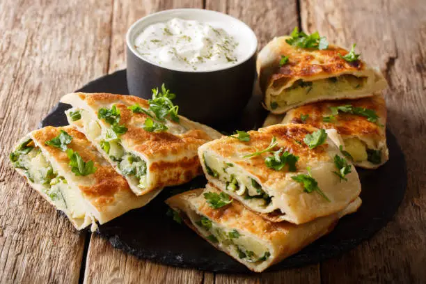 Rustic style afghan fried flatbread bolani stuffed with potatoes, green onions and cilantro close-up on the table. horizontal