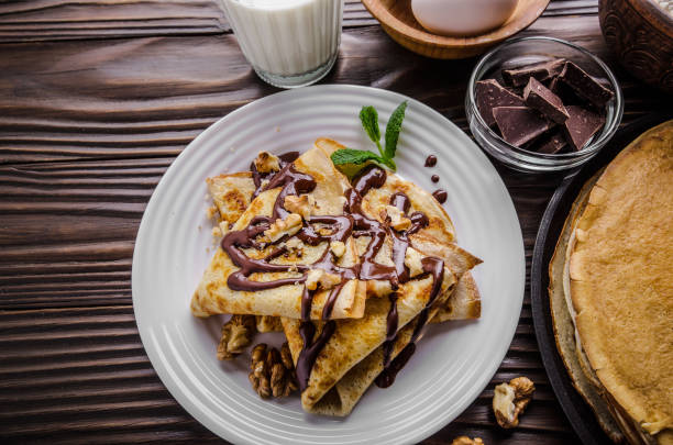 istock French crepes with chocolate sauce walnuts eggs and flour on wooden kitchen table 1165731265