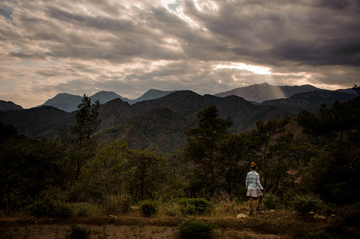 Girl standing on the beautiful landscape of the mountain under the cloudy sky between Cirali and Tekirova, Turkey