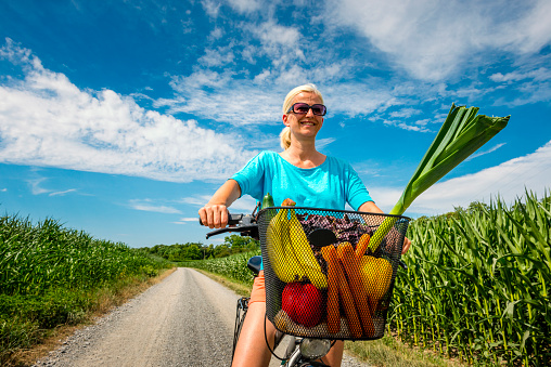 woman with bicycle and a basket full of vegetables