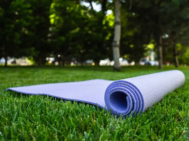 Yoga or fitness Mat. Mat for sports on the green grass in the Park. Exercise in the fresh airYoga or fitness Mat. Mat for sports on the green grass in the Park. Exercise in the fresh air