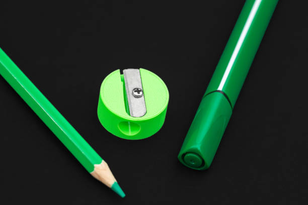 istock Green pencil, marker and pencil sharpener on black background 1165733789