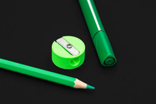 Green pencil, marker and pencil sharpener on black background