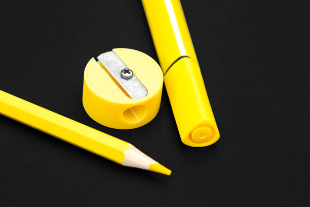 istock Yellow pencil, marker and pencil sharpener on black background 1165734035