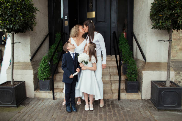 Cheerful Loving Family A front-view shot of a happy newlywed lgbtqi couple kissing each other, they are standing with their proud family on their wedding day. gay wedding kiss stock pictures, royalty-free photos & images