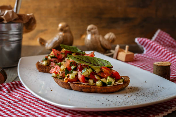 istock two bruschettes with tomato and cucumber and green leaf on a white plate on a Board table 1165738702