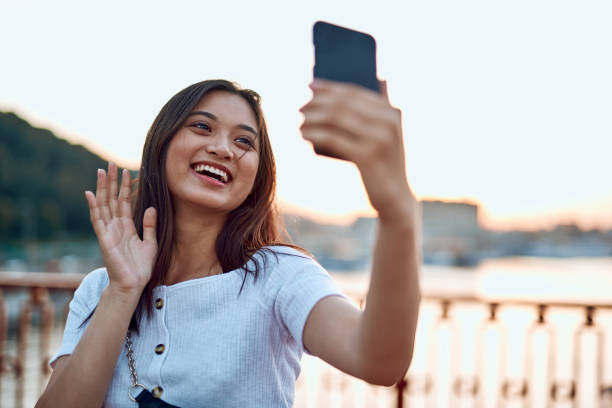 istock Happy pretty asian lady making selfie on bridge 1165739909