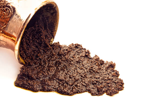Turkish brass cezve pot with fresh coffee grounds on white background.