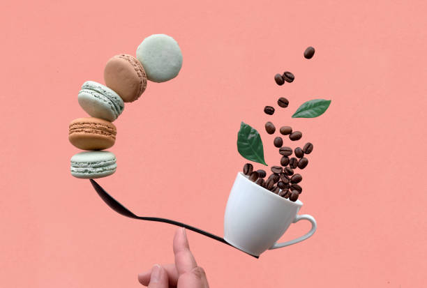 istock Balancing cup of coffee and macarons on a spoon on coral background 1165741573
