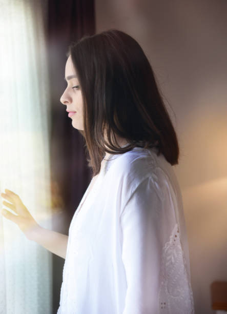istock Woman Looks Out the Window 1165752410