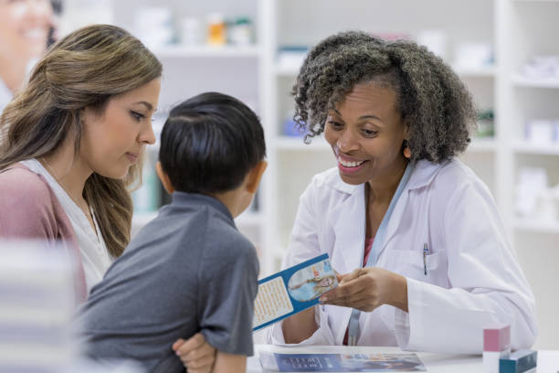 istock Pharmacist points to brochure as mother and son look 1165754724