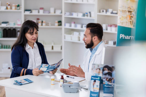 lorsque le client demande, le pharmacien explique les doses à l'aide de brochure - decisions women thinking latin american and hispanic ethnicity photos et images de collection