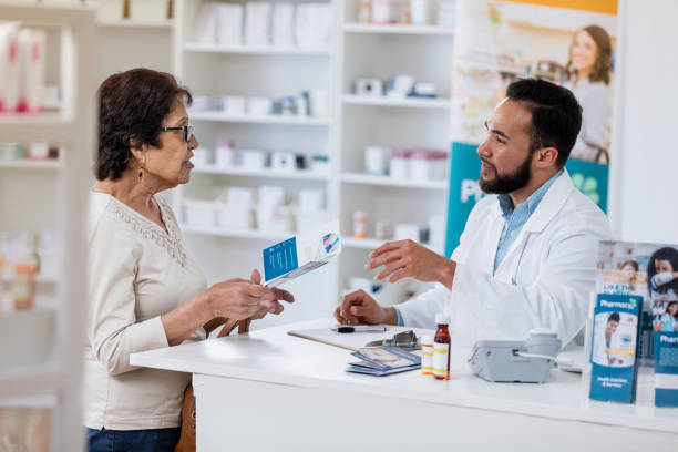 istock Senior woman asks question about drug while pharmacist listens 1165754978
